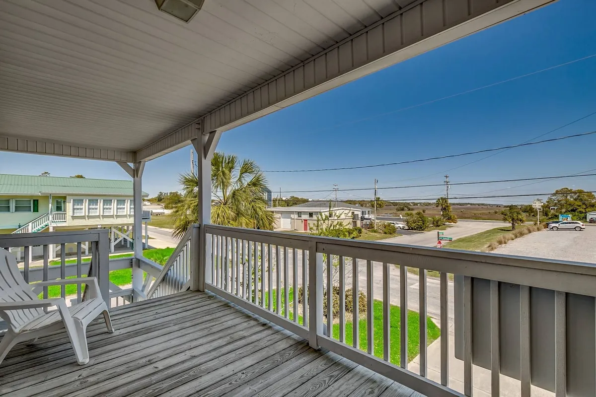 An exterior view from a balcony includes a palm tree and street view, capturing the relaxed, coastal atmosphere. The space appears tranquil, hinting at proximity to both the beach and outdoor amenities.
