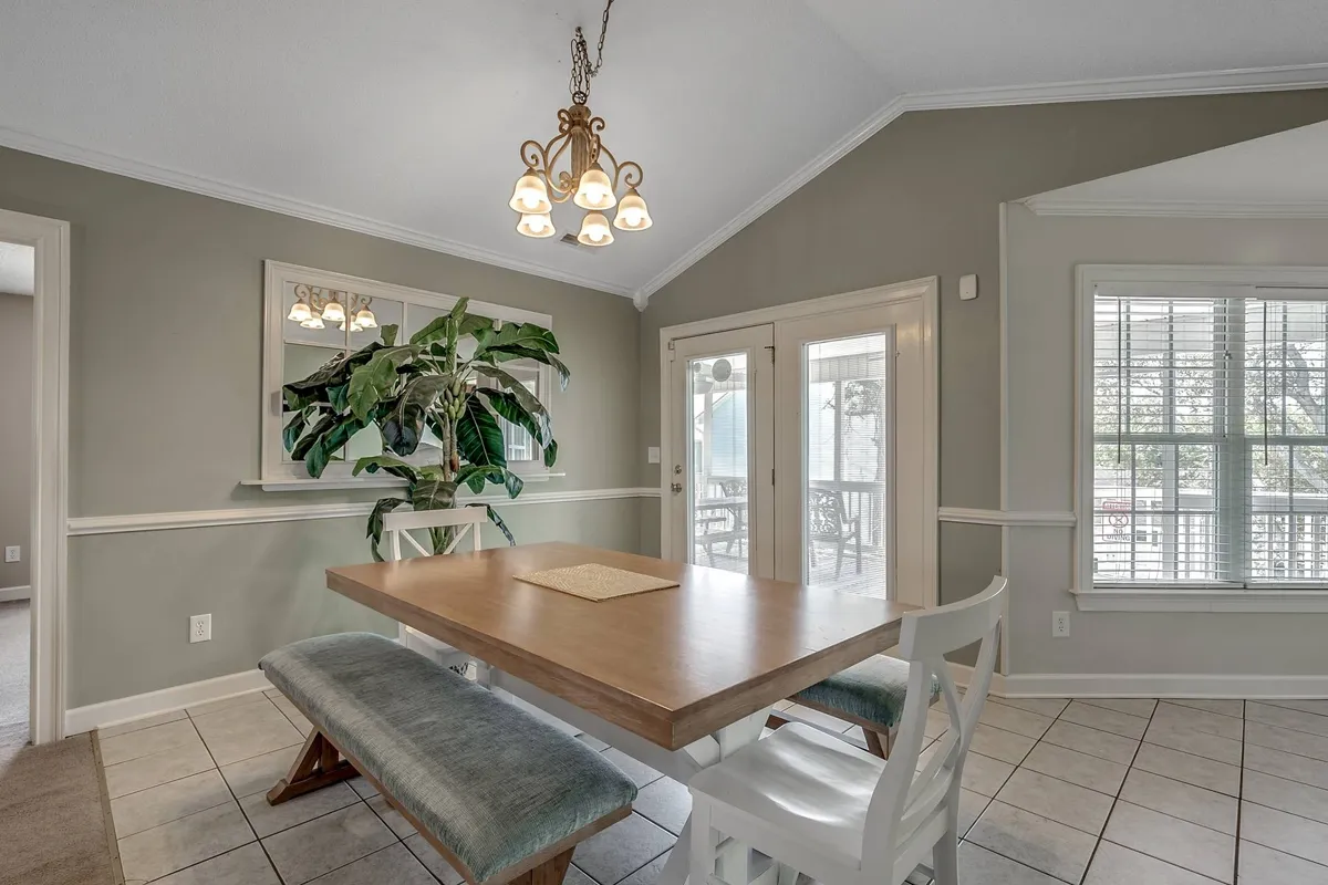 A dining area with a stylish table set under a chandelier, complemented by a potted plant and sliding doors that likely lead to an outdoor space. The overall vibe is inviting and perfect for meals, celebrations, or casual family gatherings.