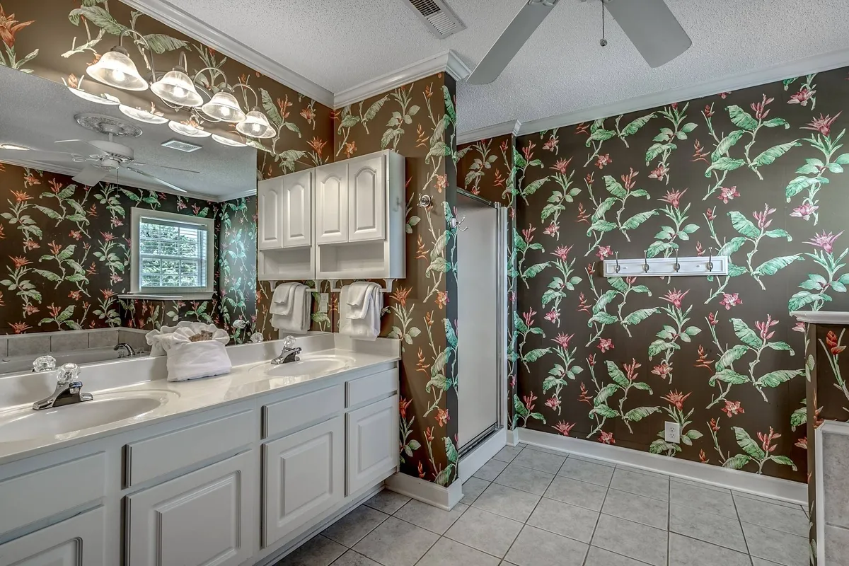 A cheerful bathroom with floral wallpaper, a double sink vanity, and bright lighting fixtures. The space is both functional and stylish, making morning routines a delight for guests.