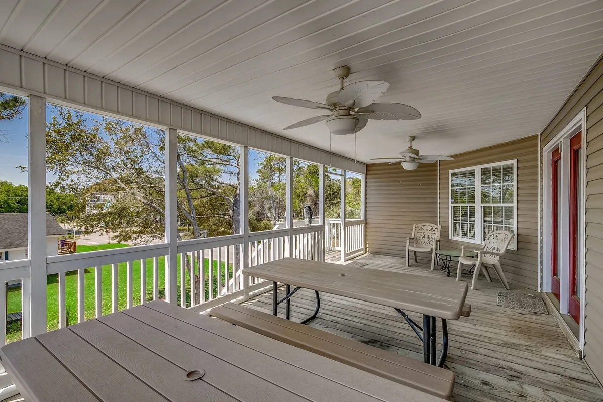 An airy, spacious porch with ceiling fans, comfortable outdoor seating, and large windows connecting the interior to the exterior. The space is ideal for relaxed meals, group conversations, or simply enjoying the fresh air.