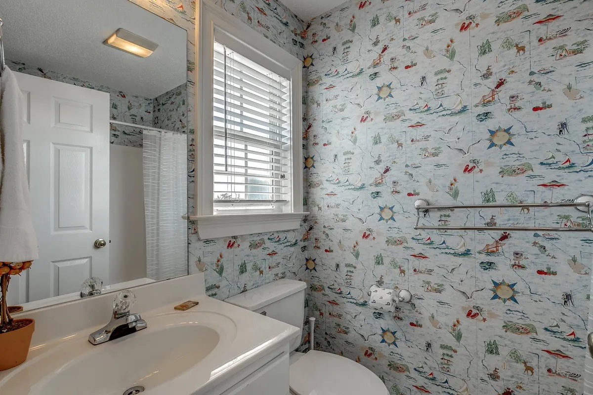 This interior image focuses on a bright and cheerful bathroom with colorful wallpaper, a sink and mirror, and a window letting in natural light. The setting suggests a refreshing spot for rinsing off after enjoying the outdoors.